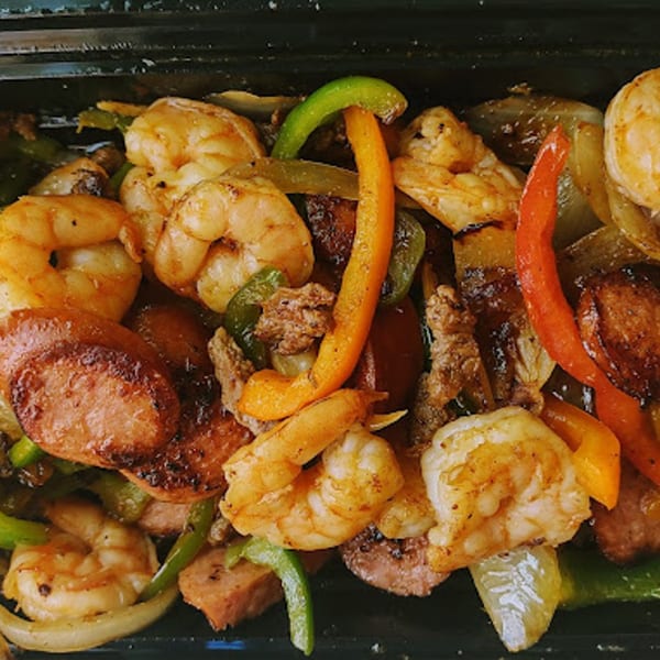 Close-up of grilled shrimp, sausage, and colorful bell peppers with onions from DON PIBIL GRILL.
